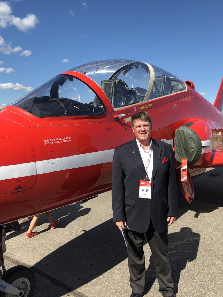 Terry Slobodian in front of red fighter jet, welcoming you to the Royal Aviation Museum