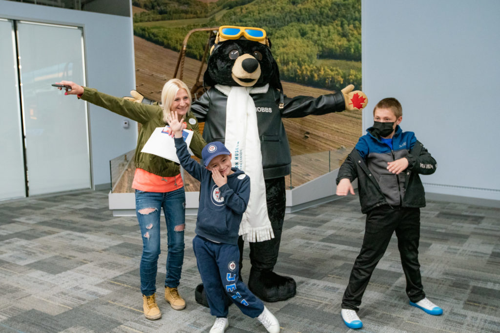 Royal Aviation Museum of Western Canada mascot Hobbs the Bear with visitors on opening weekend