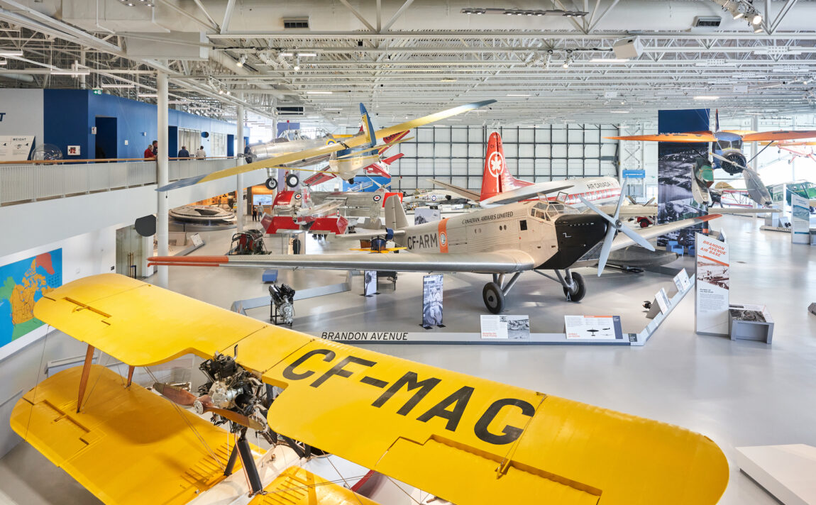 View from the second floor of the Royal Aviation Museum showing the hangar floor decorated with vintage aircraft, and some suspended from the ceiling.