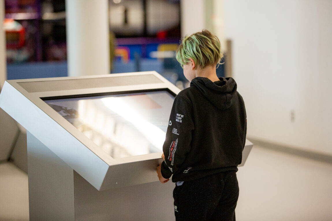 Young museum visitor stands in front of one of the new video kiosks at the Royal Aviation Museum