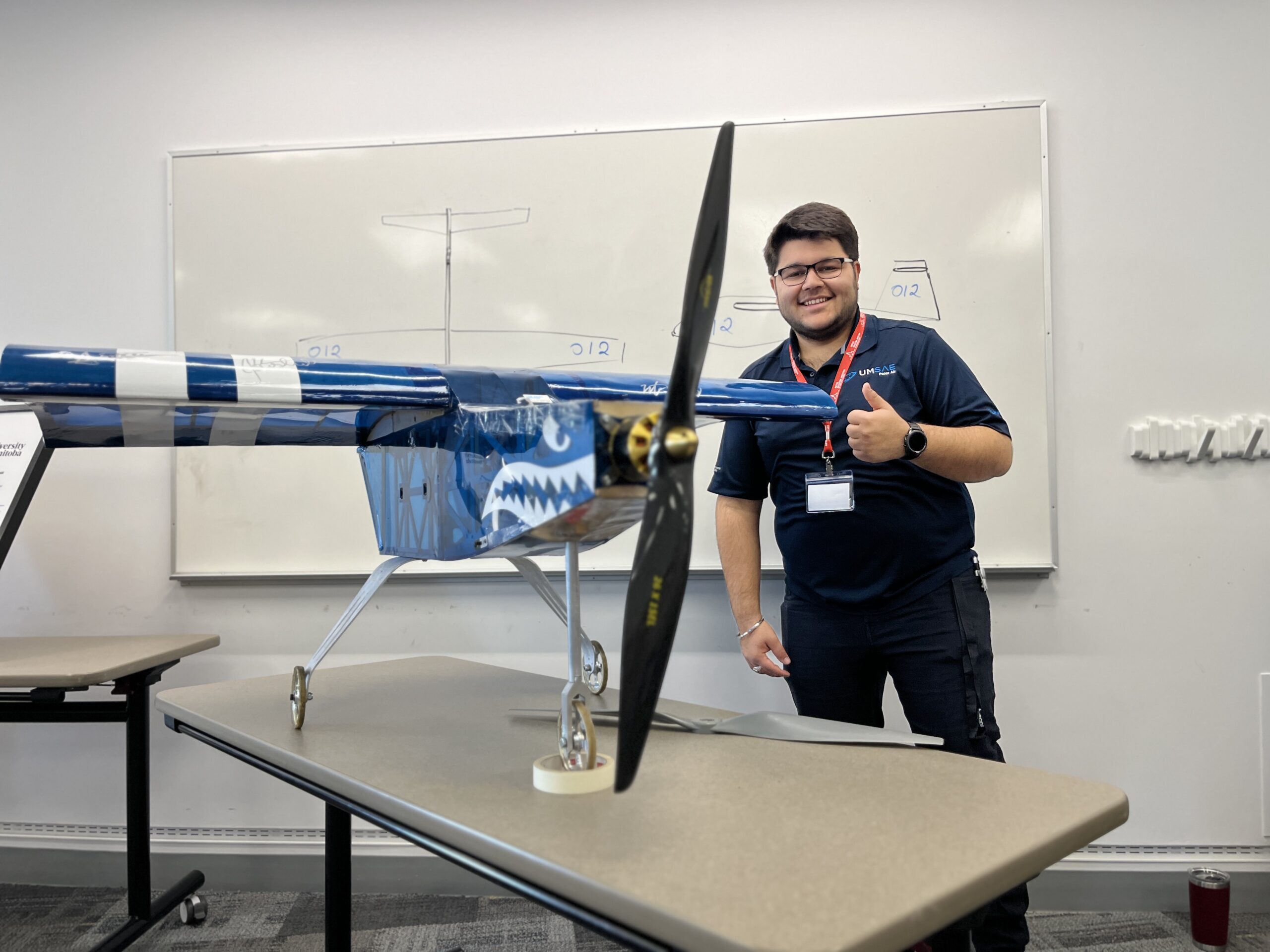 A student from the UM Price Faculty of Engineering SAE Aero team stands behind the team's winning design, giving thumbs-up