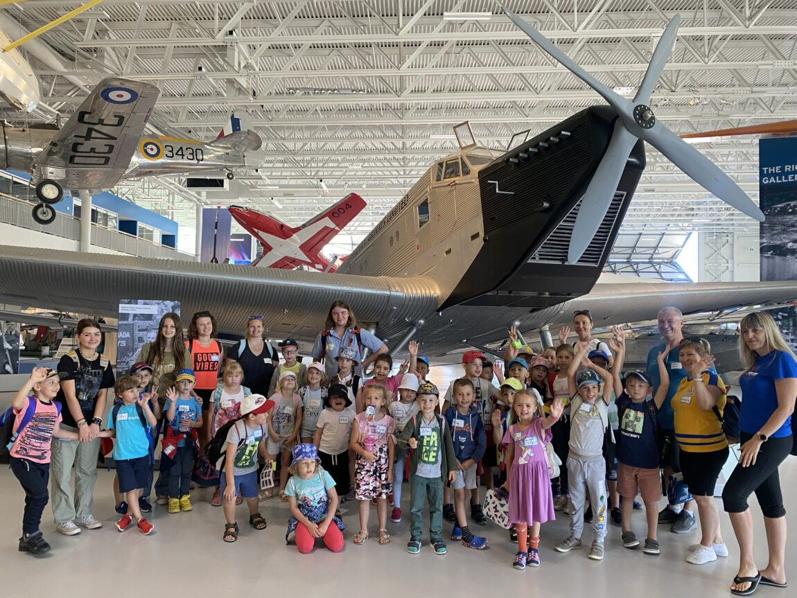 School group of young children poses in front of the Junkers at the Royal Aviation Museum