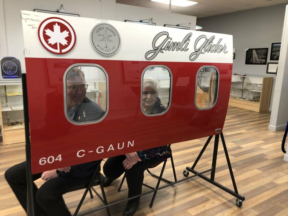 Visitors look through the windows of a section of the Gimli Glider fuselage
