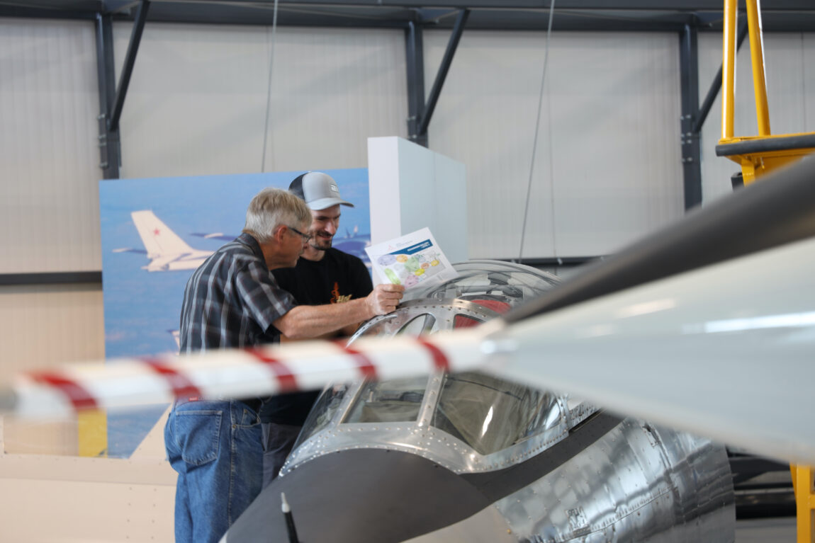 Two men, one older, one younger, look into the Starfighter trainer at the Royal Aviation Museum. Out of focus in the foreground, the nose of the museum's CF-104 Starfighter is visible