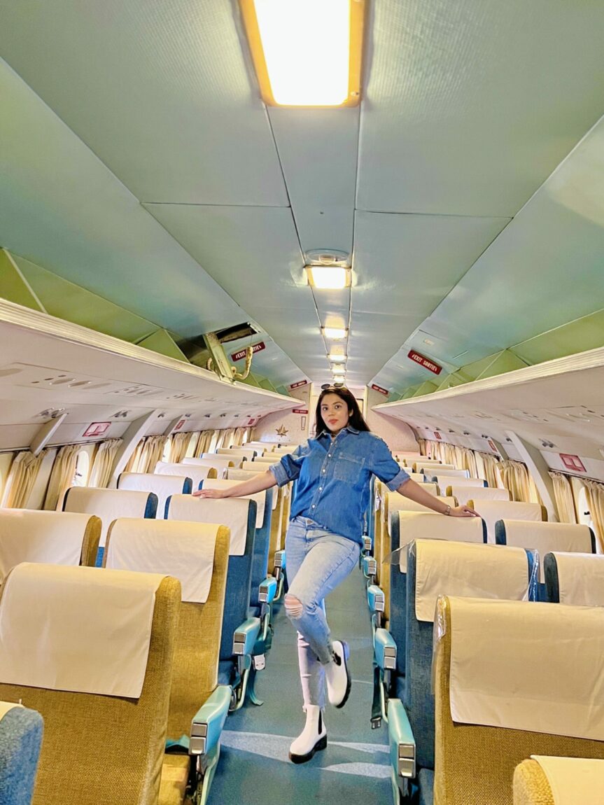 A female visitor dressed in denim poses in the aisle of the vintage Vickers Viscount passenger aircraft at the Royal Aviation Museum of Western Canada.
