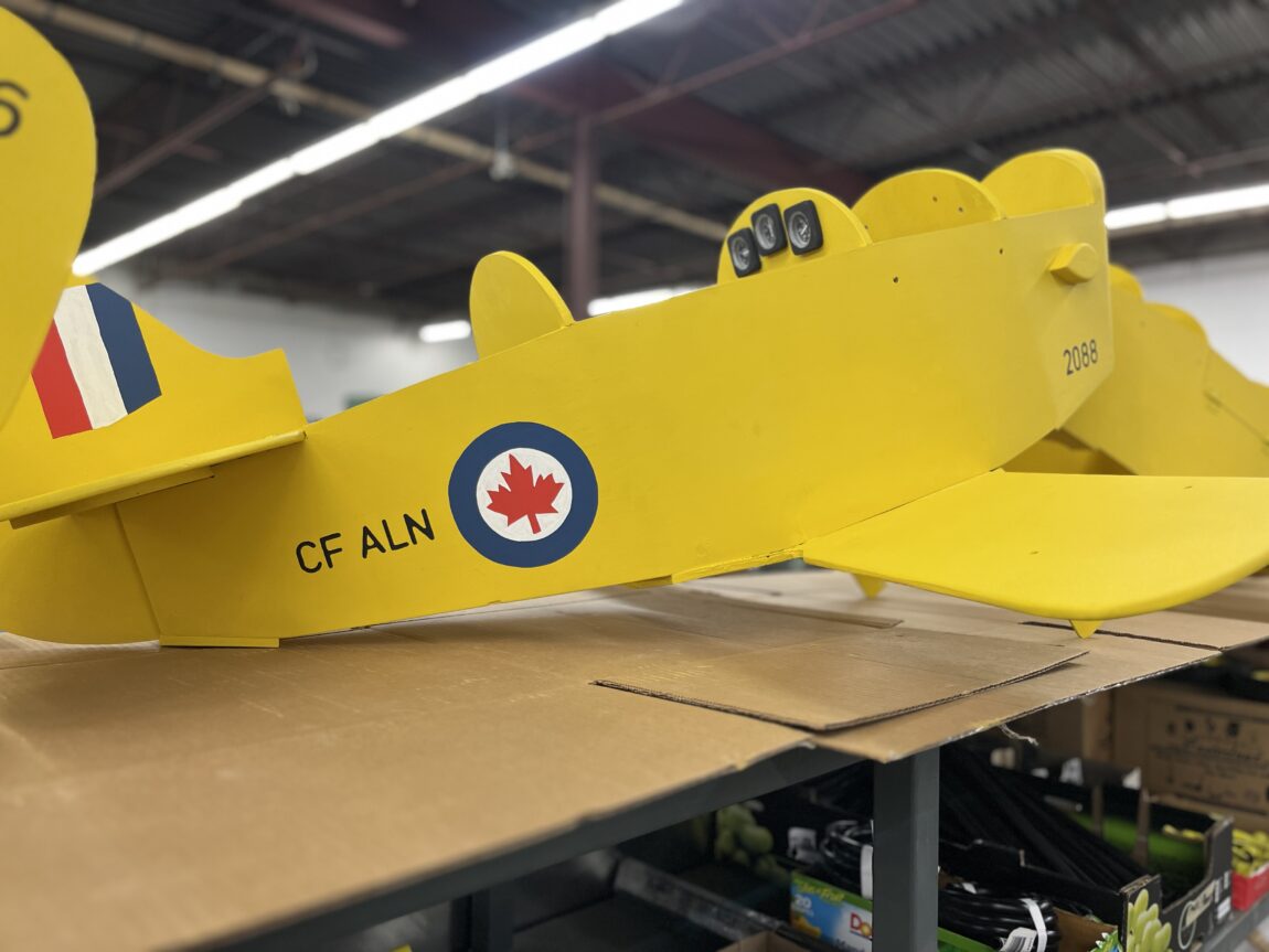 closeup of a partially completed wooden airplane. The plane is yellow with RCAF markings.
