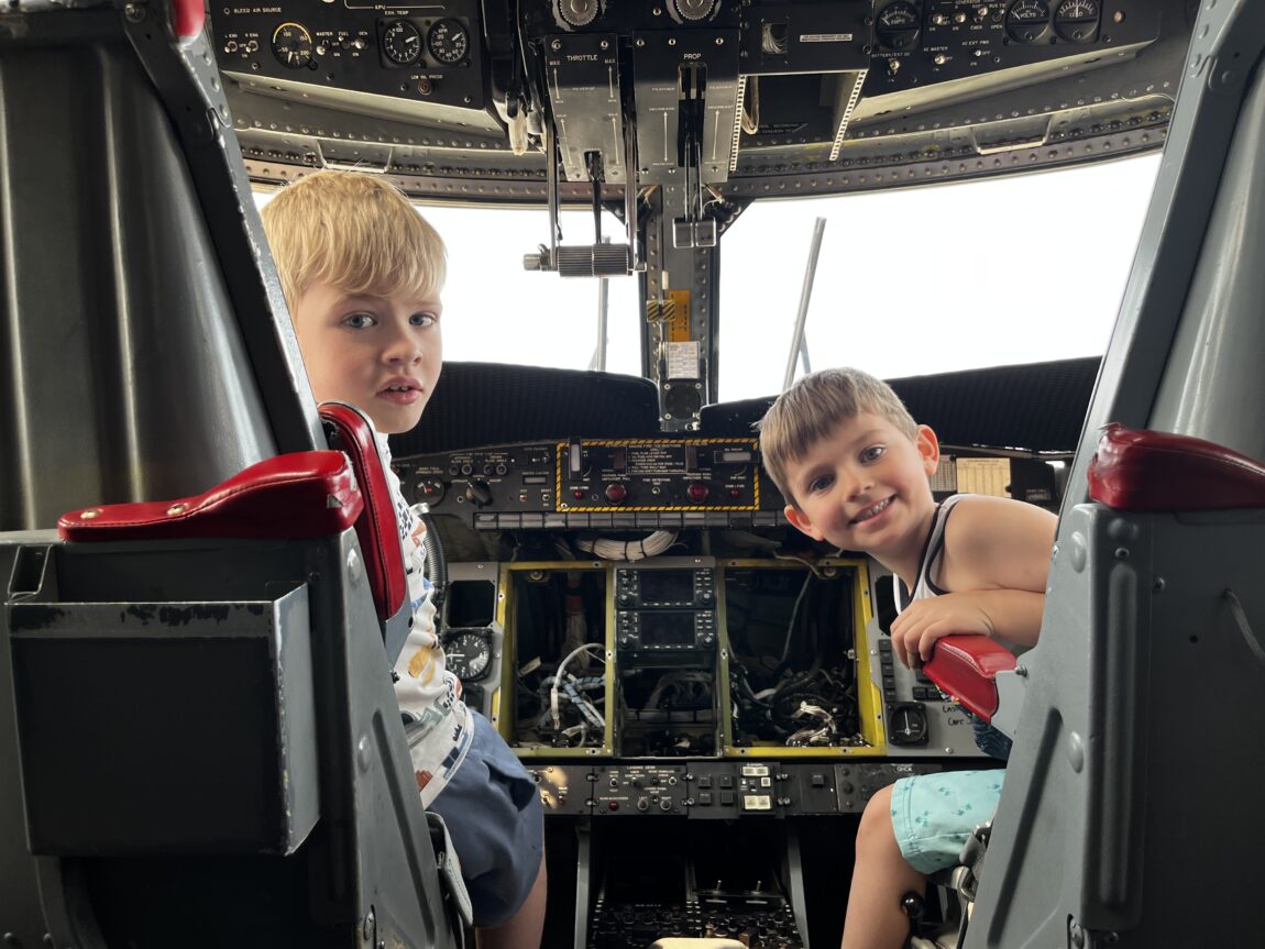 two young boys sit in the pilot and first officer seats of an aircraft