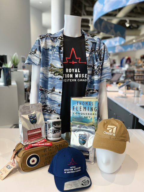 display of various gift shop merchandise including a t-shirt on a mannequin with a Hawaiian shirt overtop, books, coffee, and RCAF merchandise