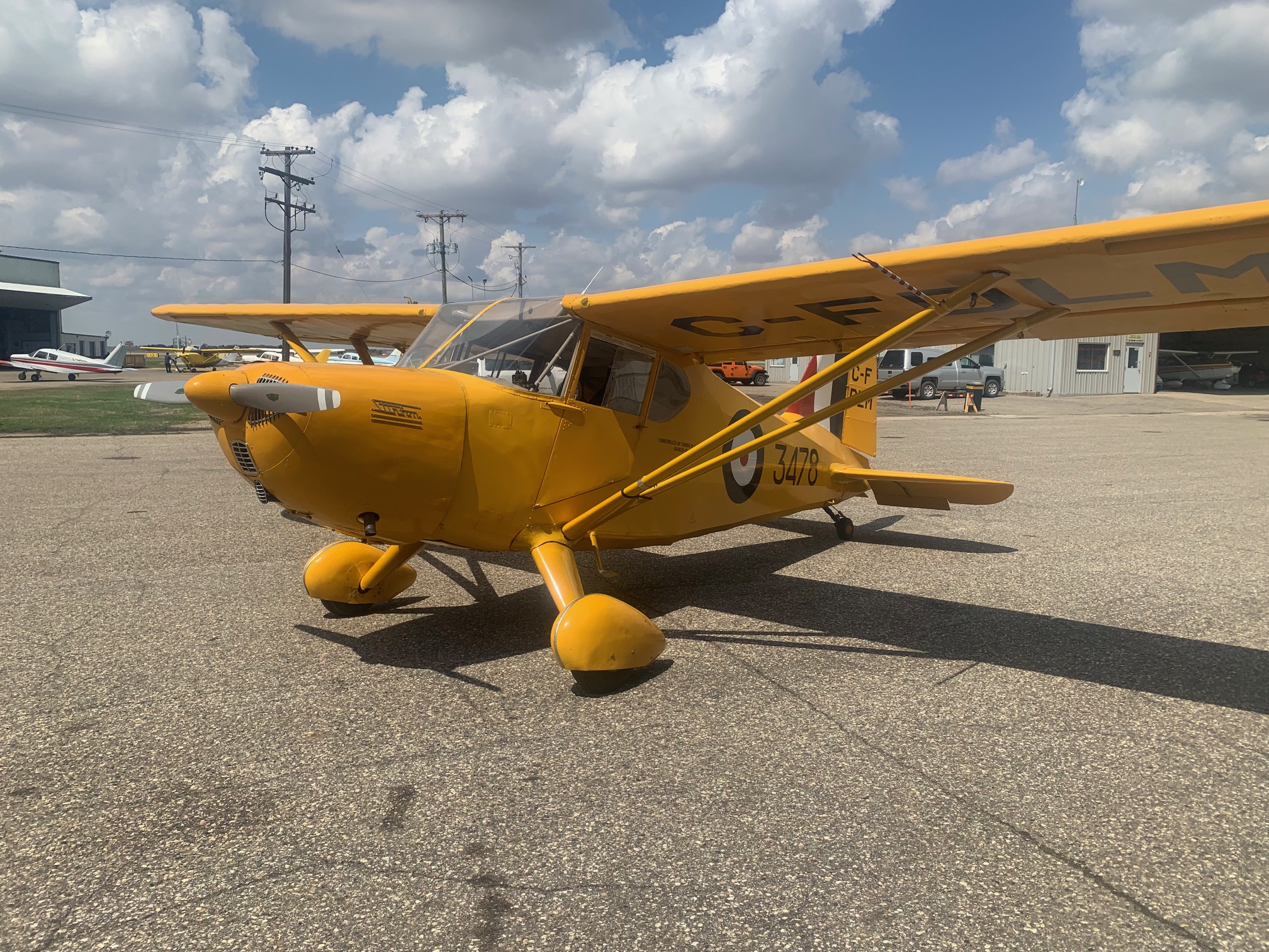 A yellow Stinson Model 105 Voyager sits on the tarmac.