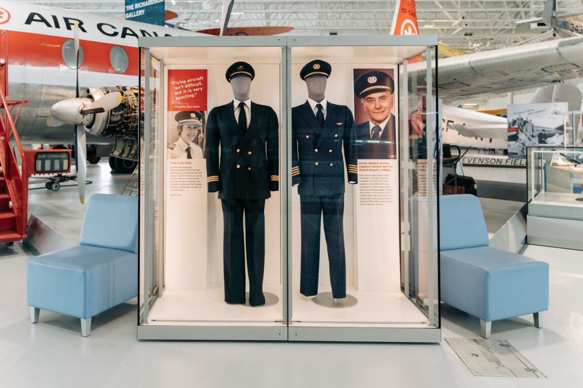 Two pilots uniforms on display on mannequins in a glass case