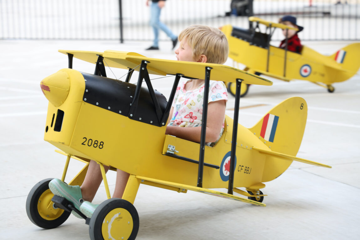 A young girl sits in a pedal plane modelled after a Tiger Moth aircraft at the Royal Aviation Museum of Western Canada