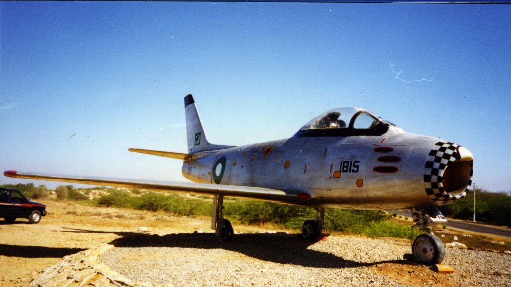 A Canadair Sabre MK 6 with Pakistan Air Force livery parked on gravel under a blue sky.  