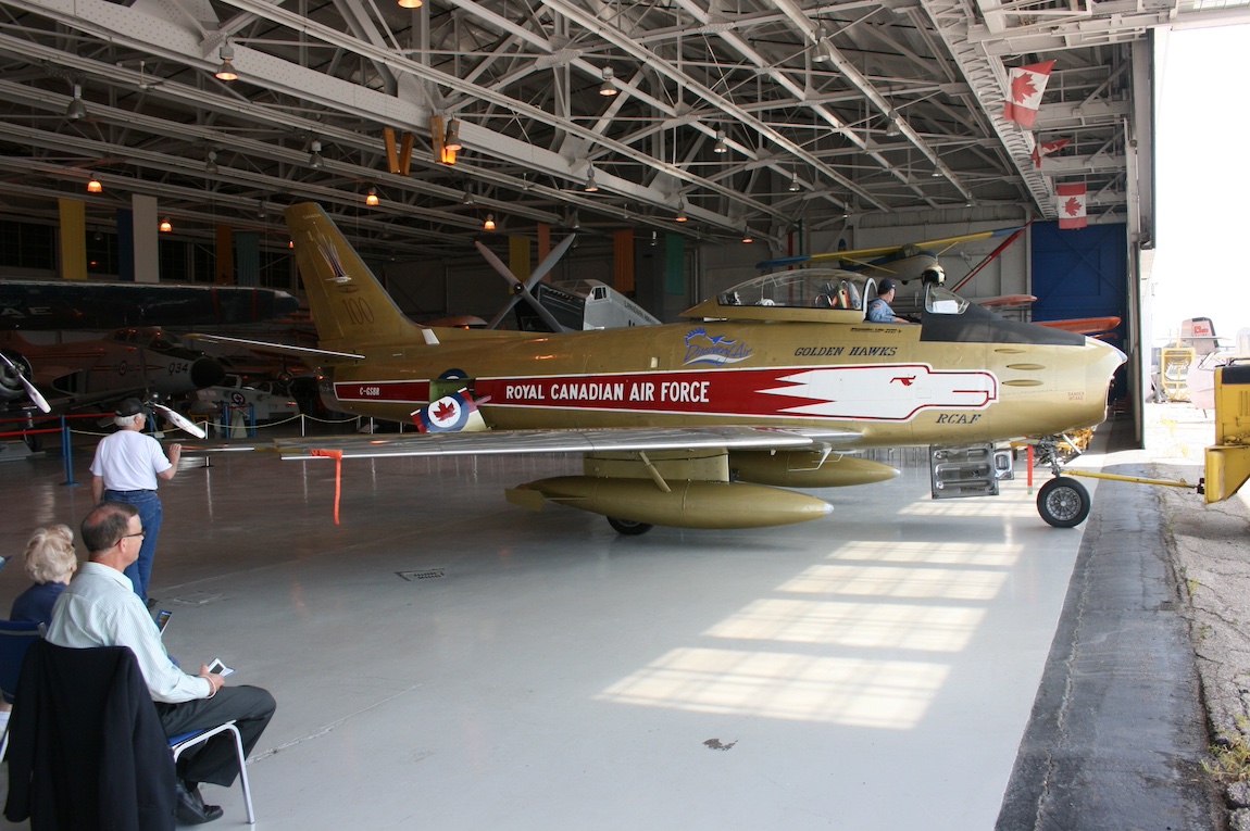 Vintage fighter jet parked inside a hangar with the overhead door open.