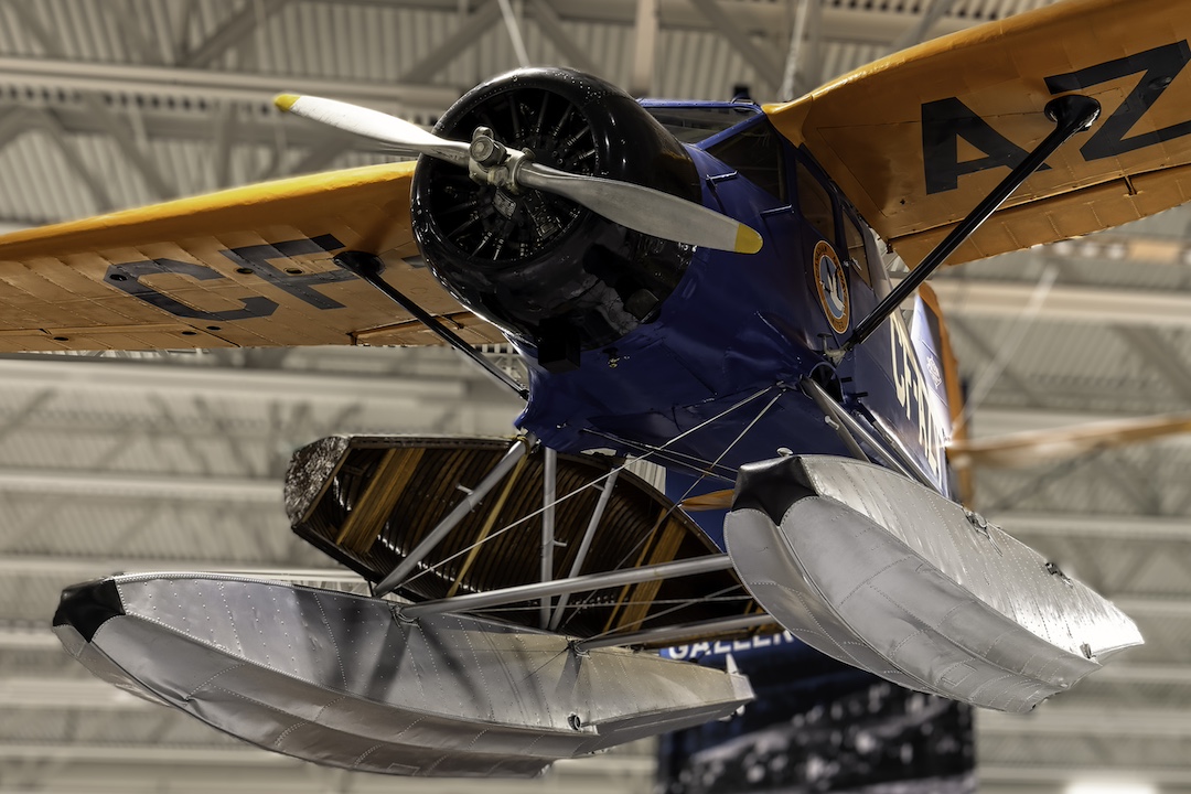 Closeup of a Stinson Reliant aircraft suspended from the ceiling of a museum.
