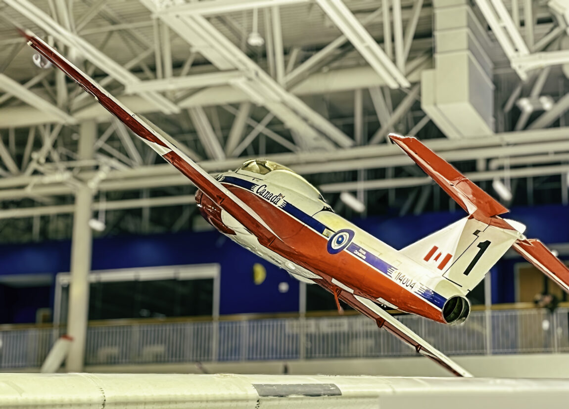 A CL-114 Tutor painted in Snowbird livery hangs suspended from the ceiling of the Royal Aviation Museum