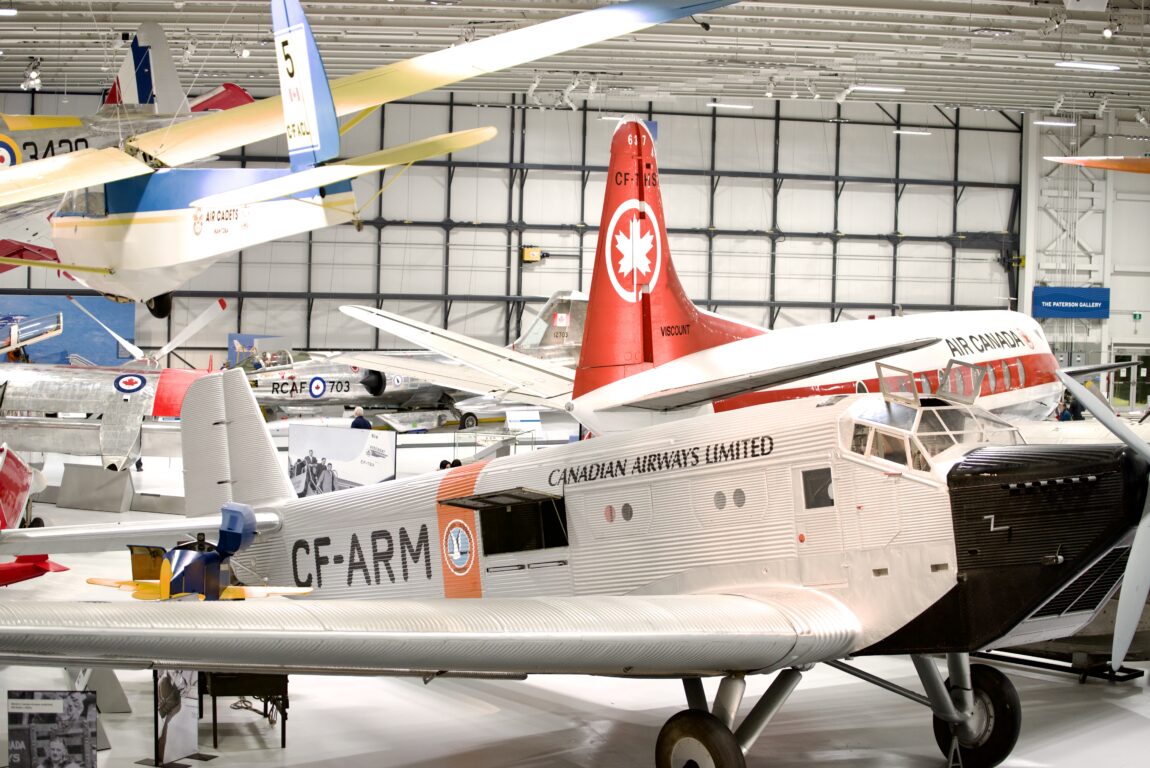 Vintage aircraft on display an aviation museum. In the foreground of the image is a Junkers Ju-52/1m, a large cargo plane from the early part of the 20th century.