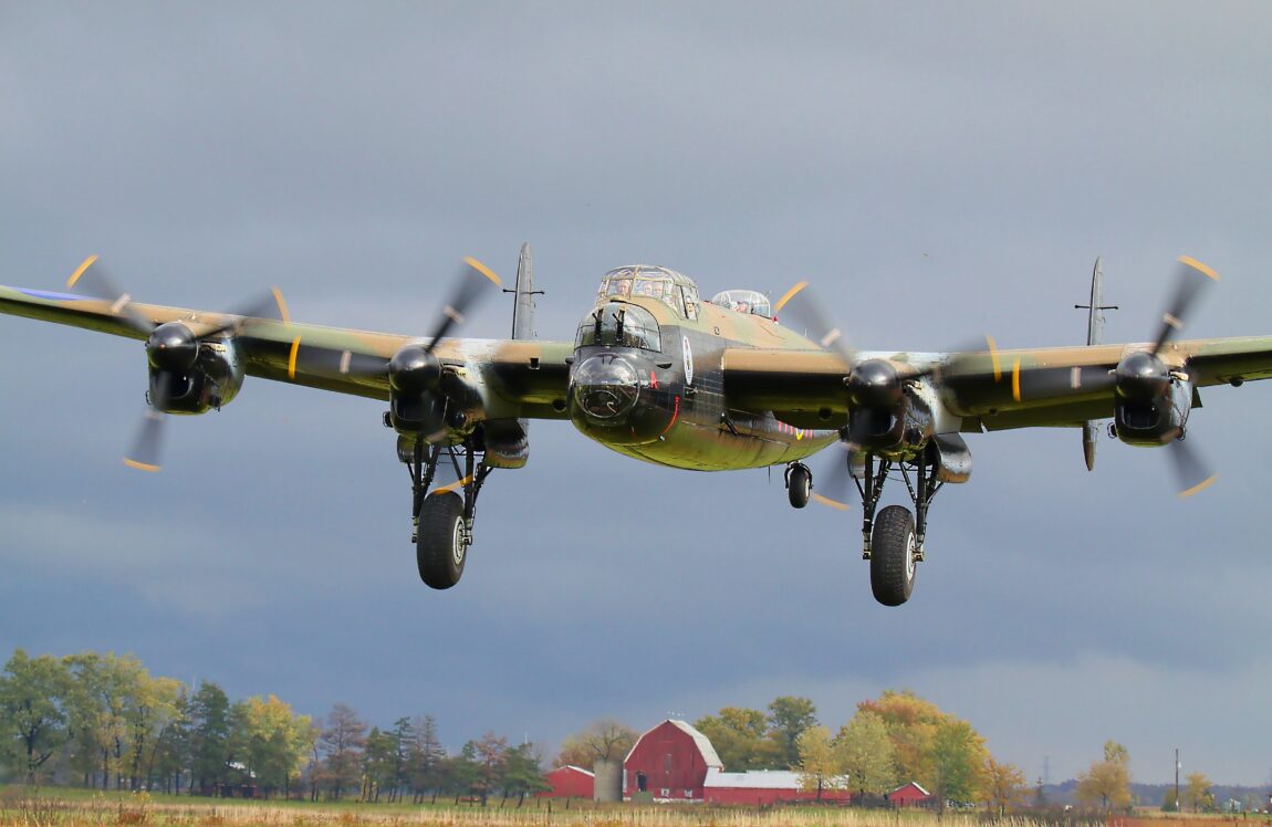 Avro Lancaster aircraft flying low over a rural property