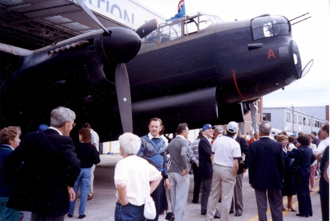 A crowd of tourists stand next to an Avro Lancaster